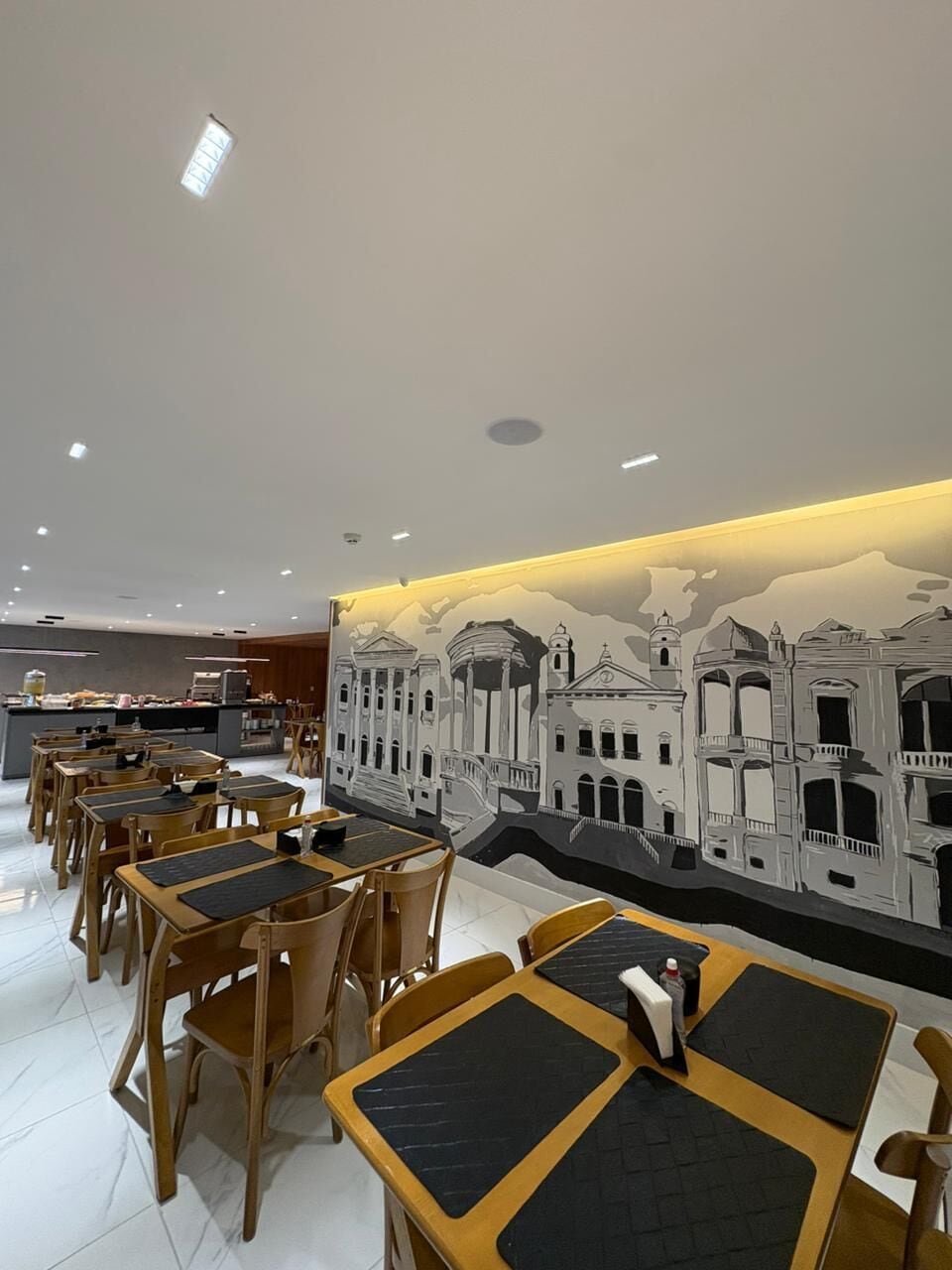 Un restaurante con mesas y sillas, un mural en la pared y una barra con productos alimenticios.