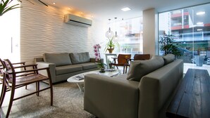 A modern living room with a sofa, chairs, a coffee table, and a large window offering a view of the outside.