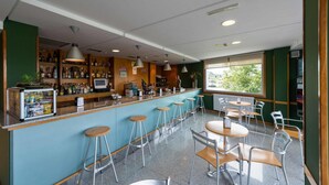 Uma área de bar com banquetas, um balcão com garrafas e vista pela janela.
