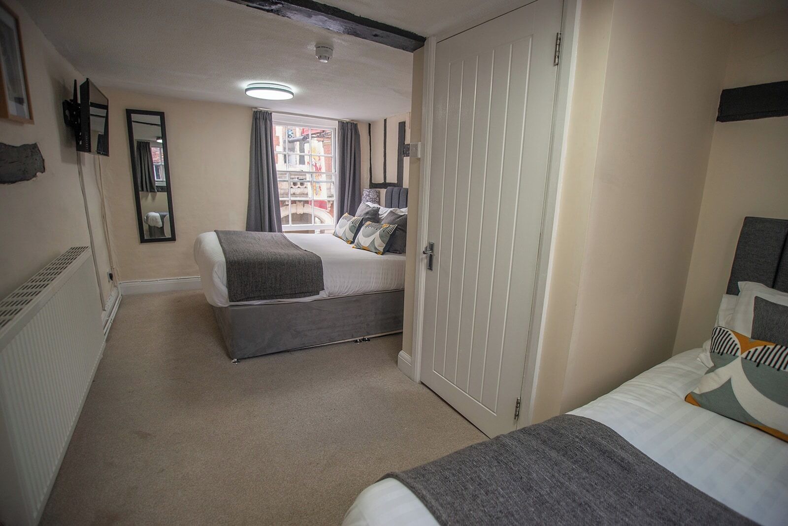 A bedroom with a bed, a wardrobe, a mirror, and a radiator.