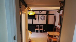 A narrow stairway leading to a room with a bed, a small table, and two chairs. A clock is visible on the wall. - The Olde Kings Arms (Hemel Hempstead)