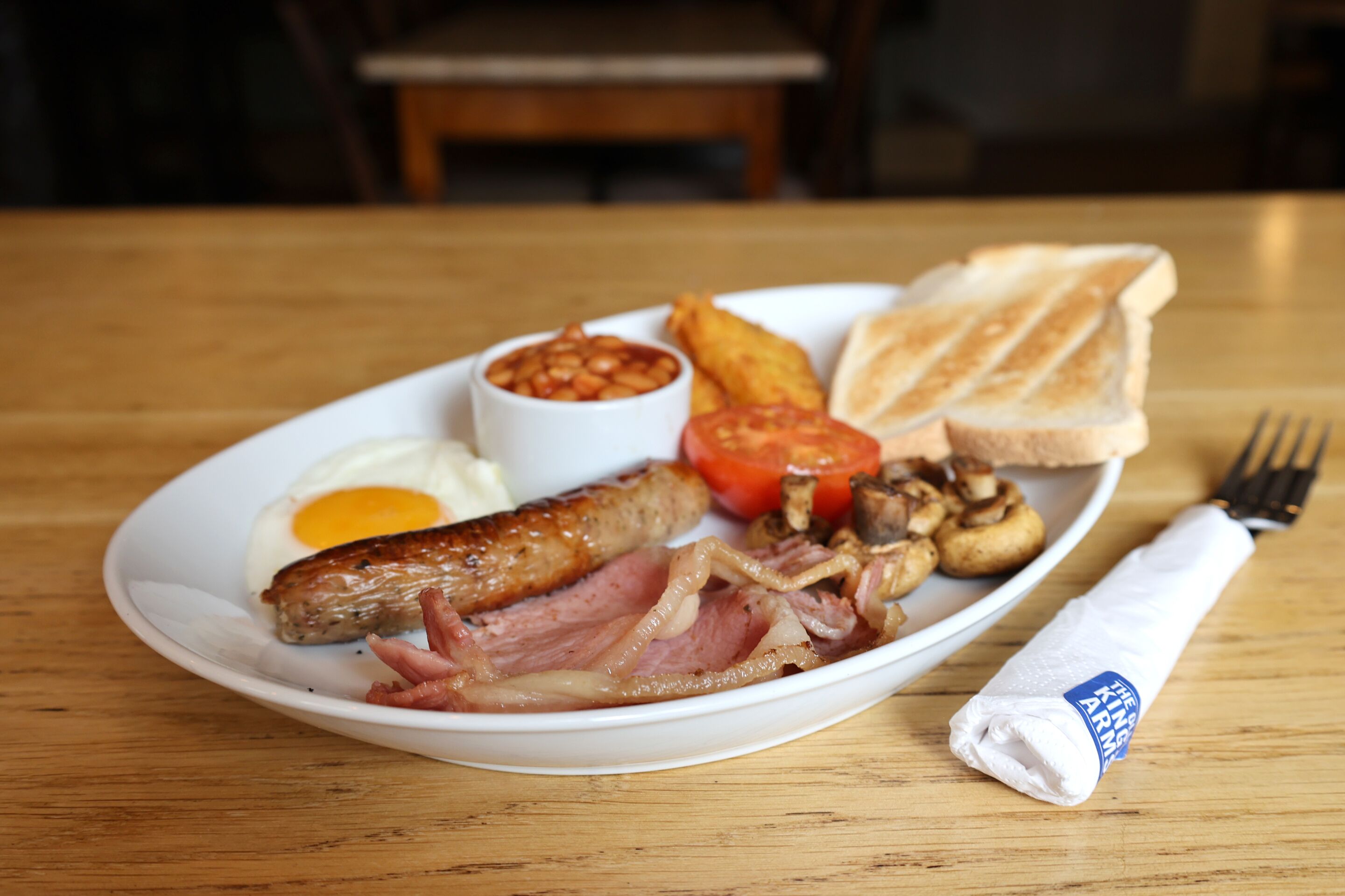 Une assiette de nourriture pour le petit-déjeuner comprenant des œufs, des saucisses et des toasts.