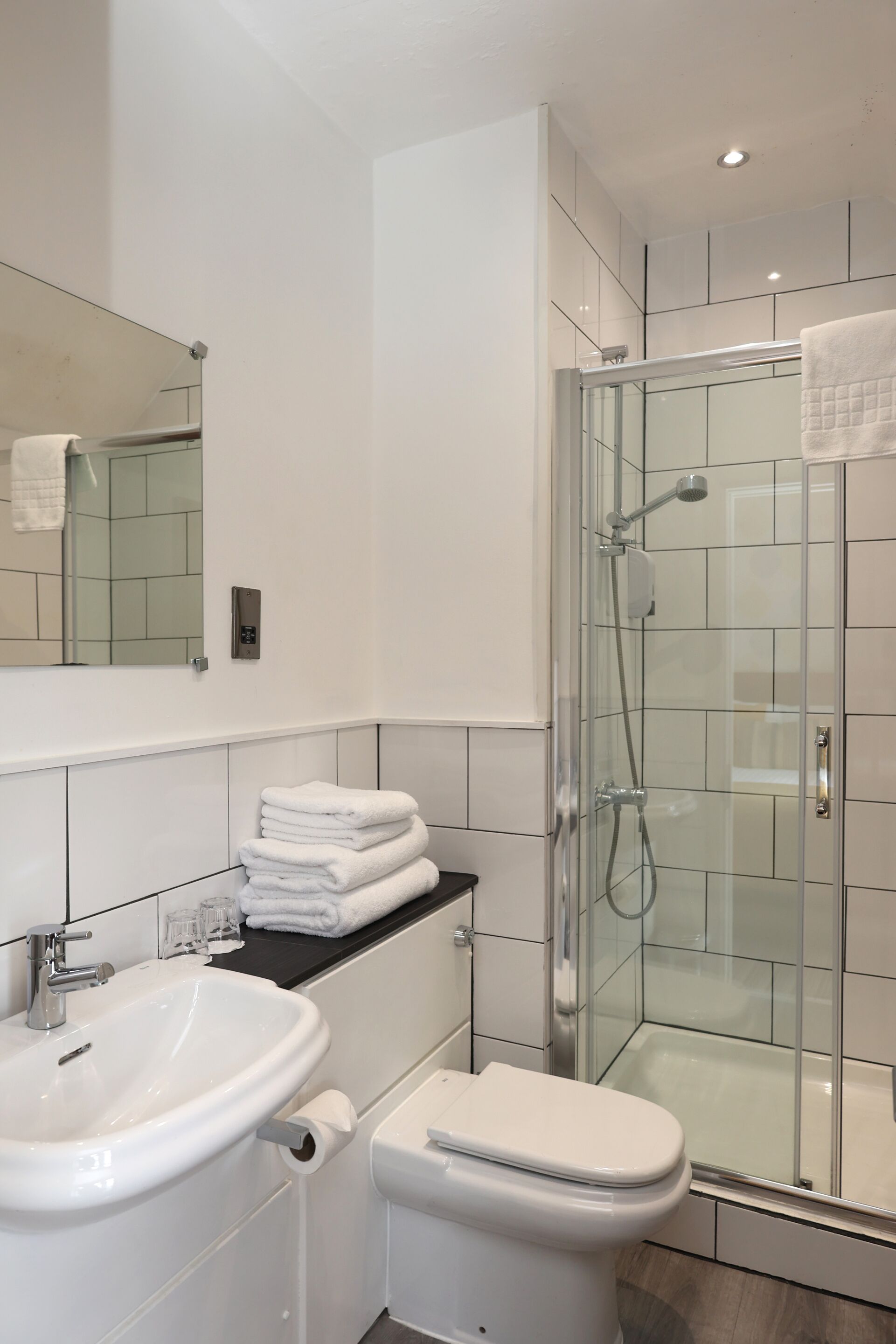 A modern bathroom with a glass-enclosed shower, a white sink, and a toilet.