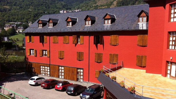 Un bâtiment rouge avec de nombreuses fenêtres et un balcon orné de plantes en pot.