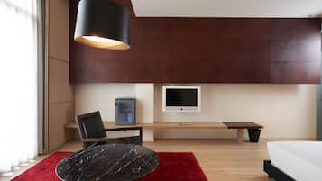 A modern bedroom with a bed, a desk, a chair, a TV, and a red rug.