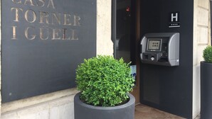 L’entrée d’un hôtel, avec une enseigne indiquant « CASA TORNER I GUELL » et un parcmètre.