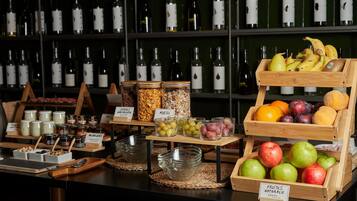 Un bufé con diferentes opciones de comida y una cava de vinos al fondo.
