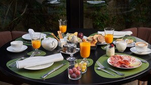 Une table de petit-déjeuner avec des assiettes remplies de nourriture, des verres de jus d’orange et une tasse de café.