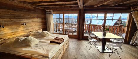 A cozy wooden cabin room with a bed, a dining table, and chairs.