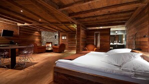A wooden cabin interior with a bed, a desk, and a fireplace. - Hôtel de l'Etrier (Crans-Montana)