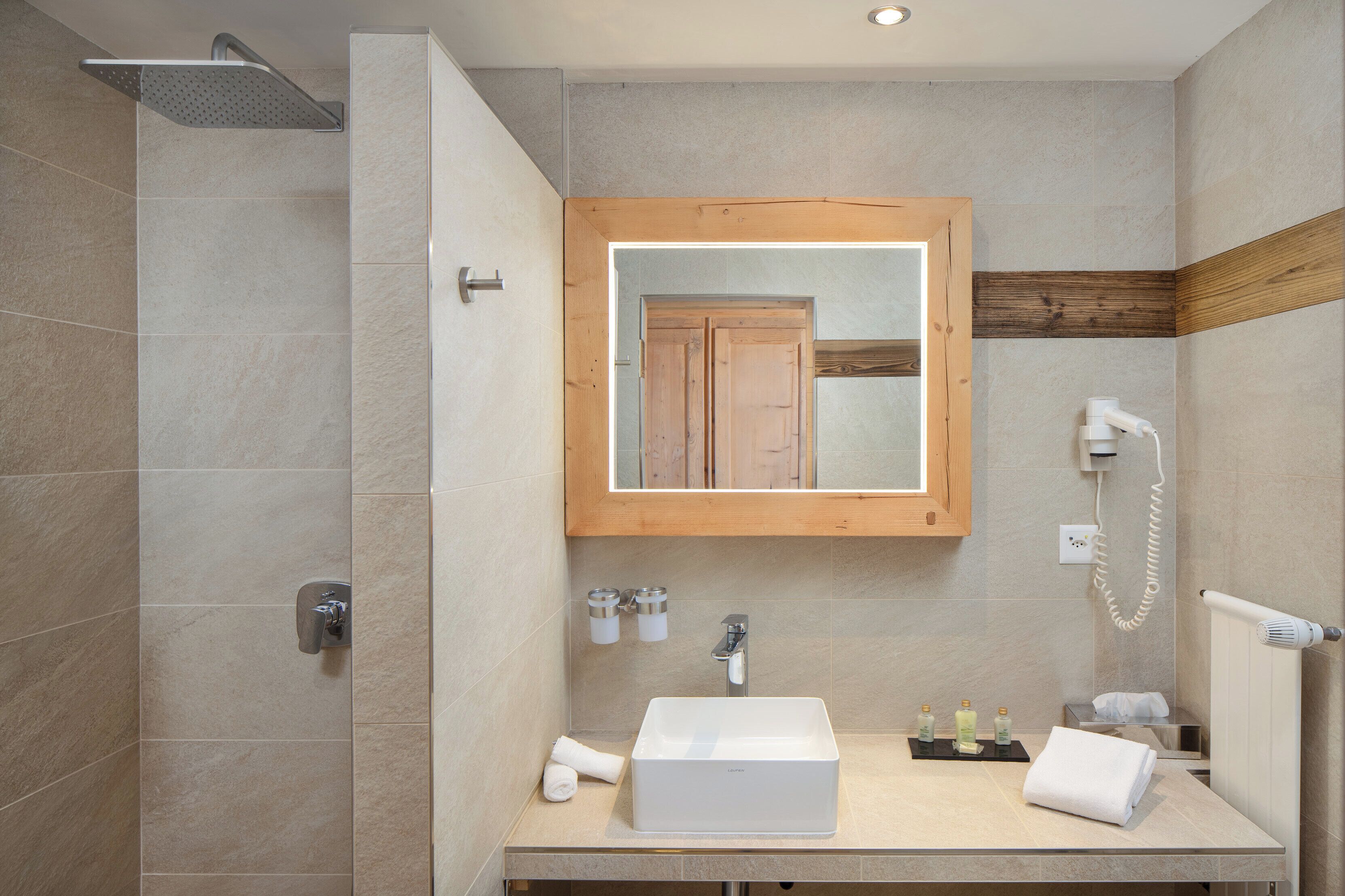 A modern bathroom with a shower, a sink, a mirror, and a towel rack.