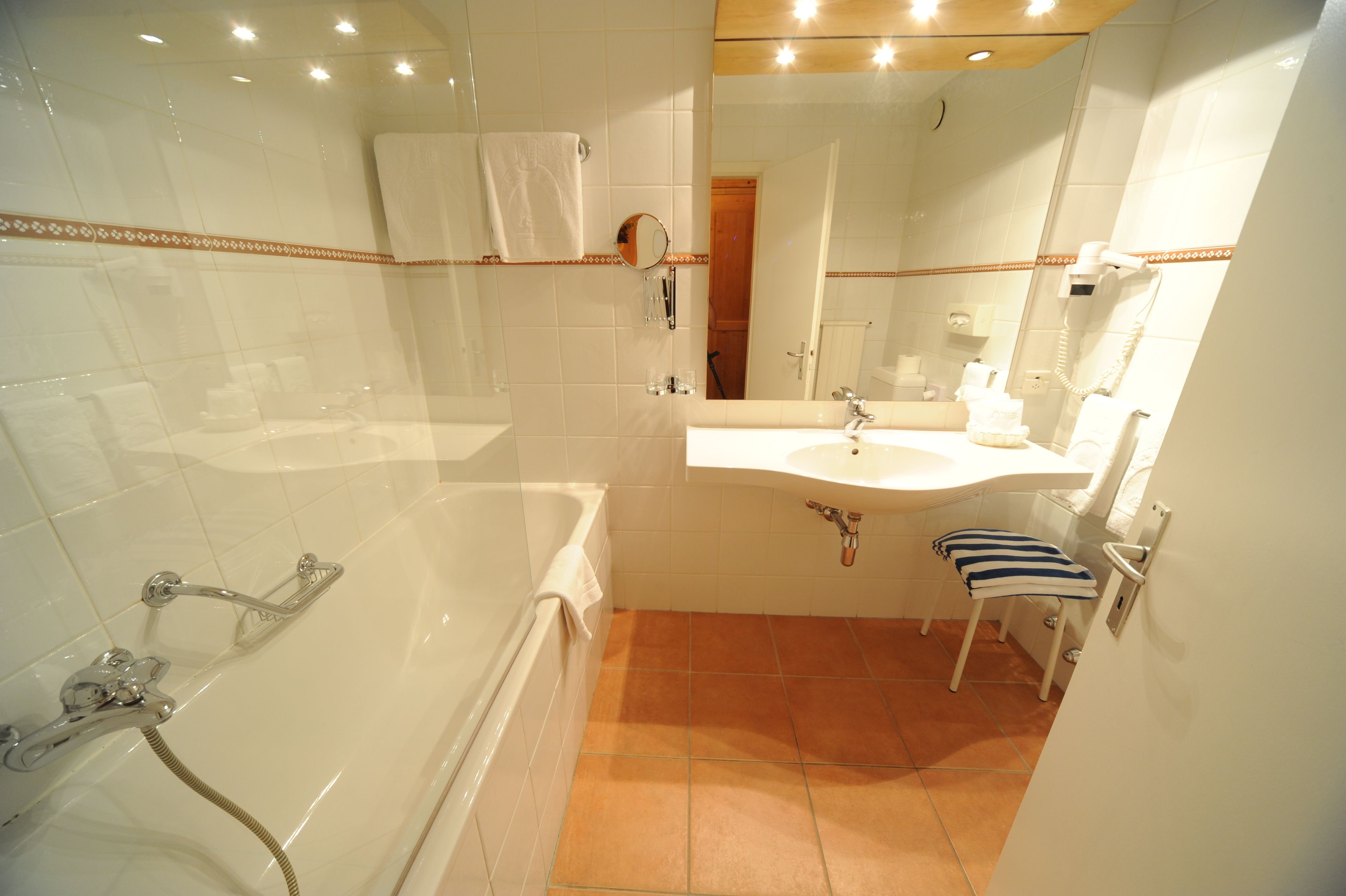 A bathroom with a bathtub, a sink, a mirror, and a towel rack.