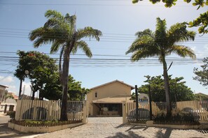 A hotel entrance with a paved driveway, palm trees, and a gated entrance. - Hotel Pousada do Sol (Aracaju)