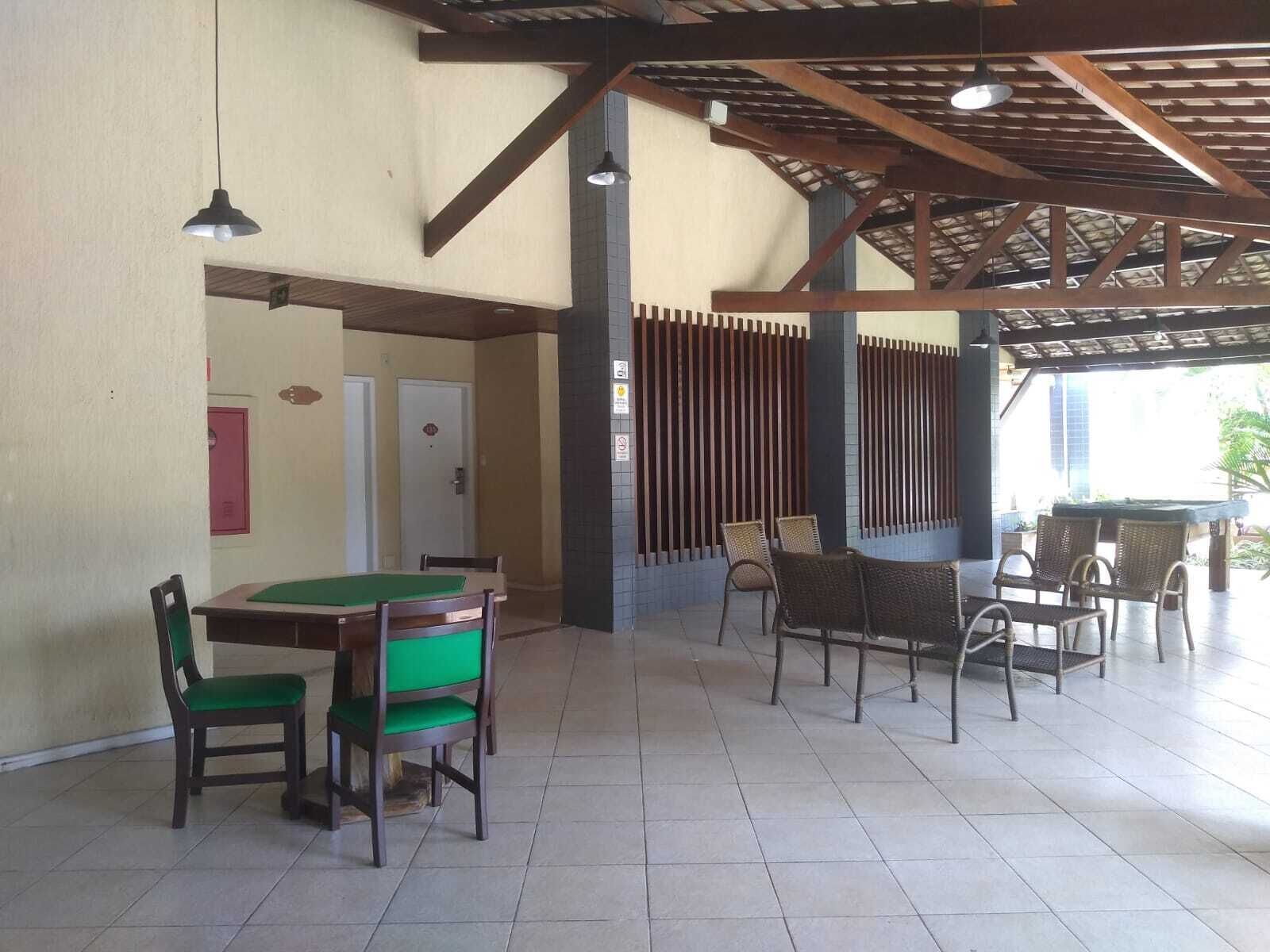 A covered outdoor area with a pool table, chairs, and a seating area with tables and chairs.