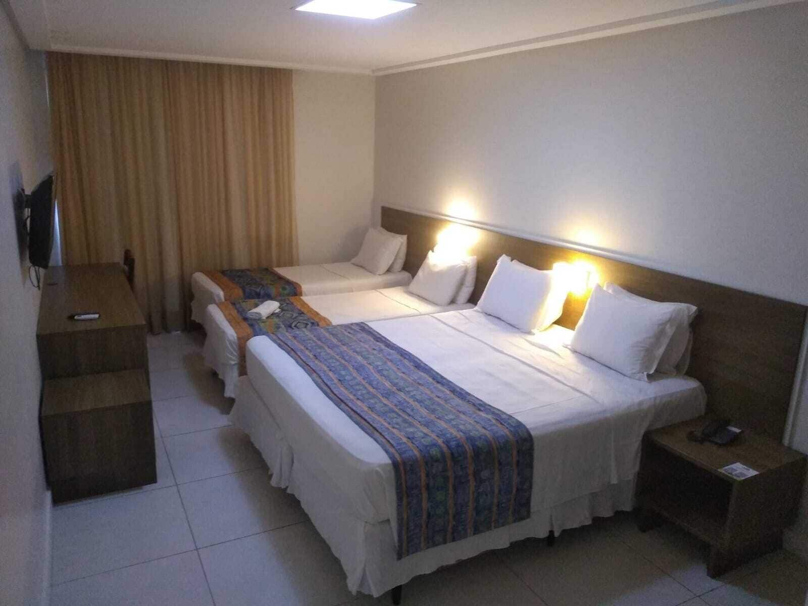 Une chambre d’hôtel avec deux lits, un bureau, une télévision et une table de chevet.