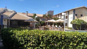 Una piscina al aire libre, sombrillas, sillones reclinables de piscina