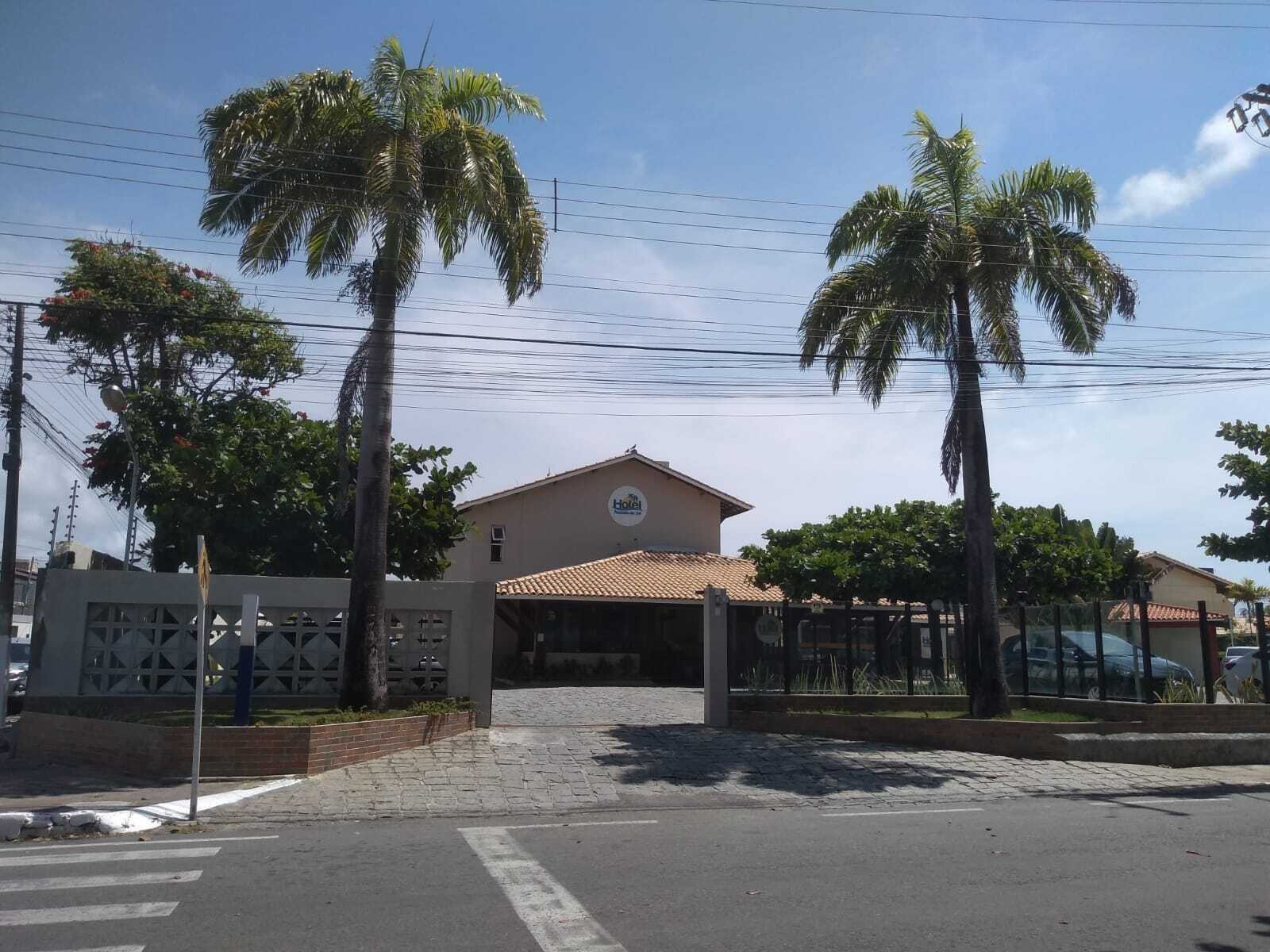 A hotel with a tiled roof, a covered entrance, and palm trees in the foreground.