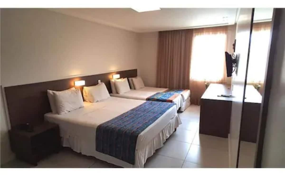 Una habitación de hotel con dos camas, un escritorio y un televisor.