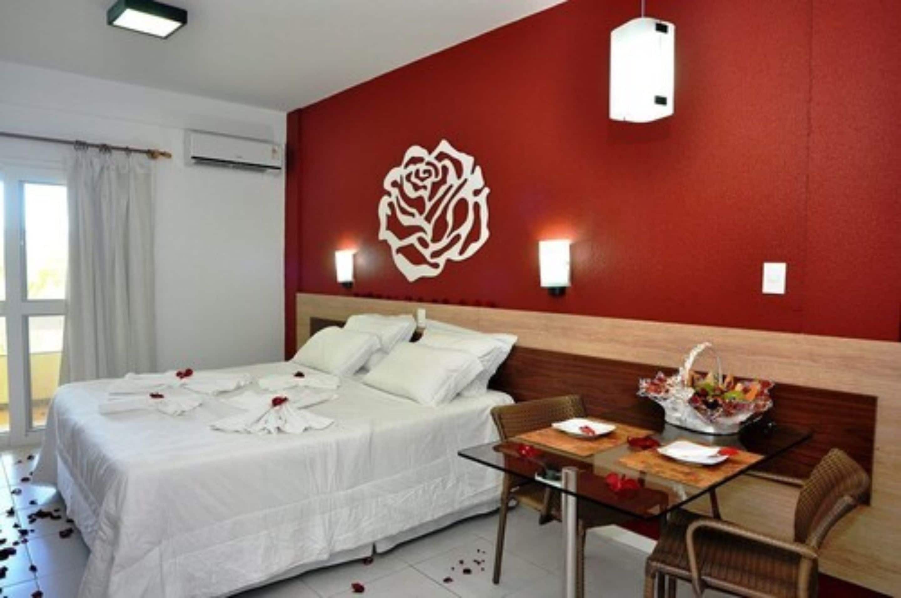 Ein Hotelzimmer mit einem großen Bett, einem Esstisch mit Stühlen und einer Wanddekoration in Form einer Rose.