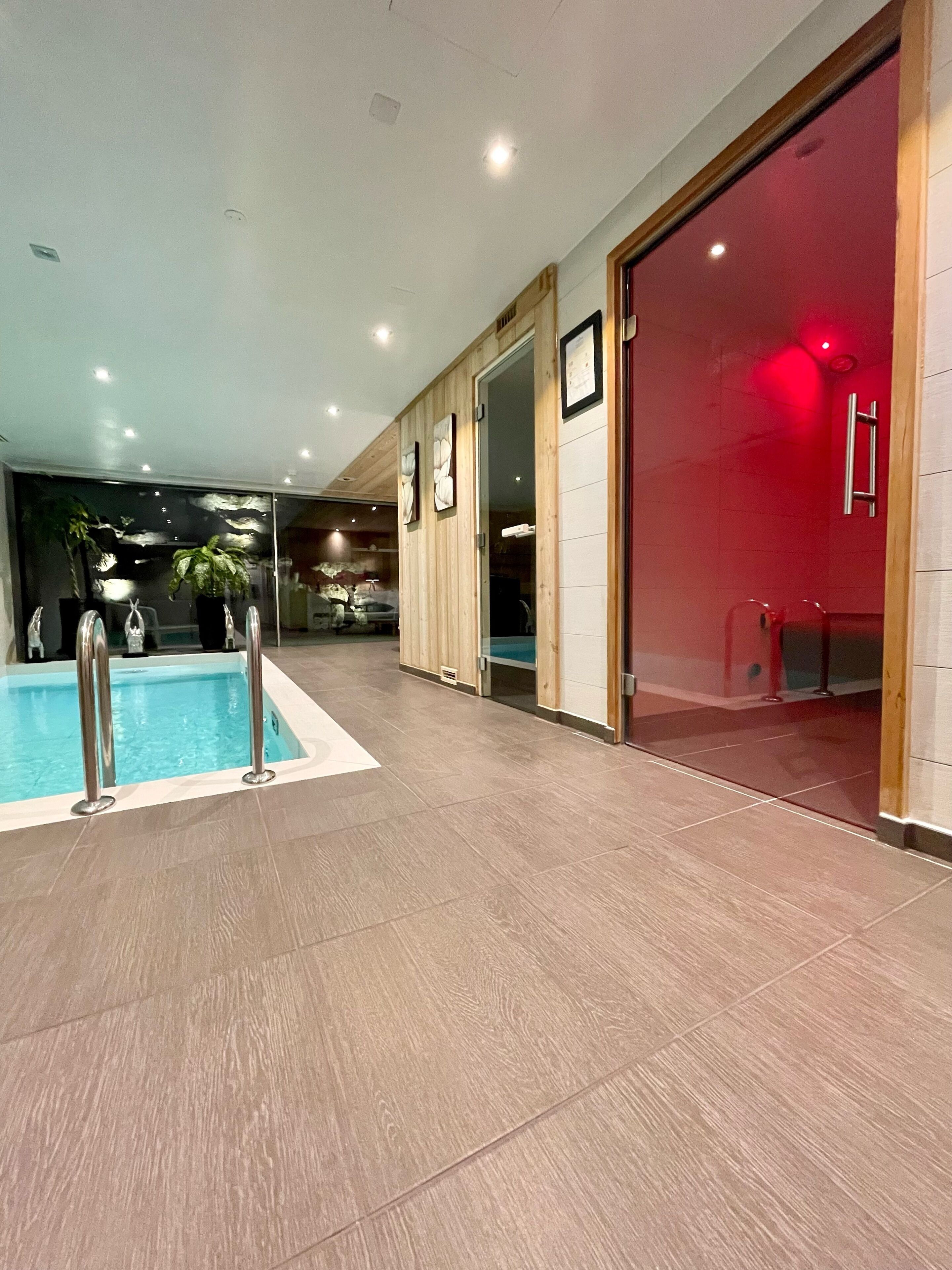 Une piscine intérieure dotée d’un plancher en bois et de rampes en métal.