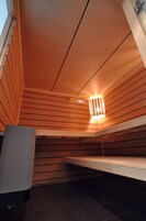 Quarto com paredes de madeira, um banco e um lustre.