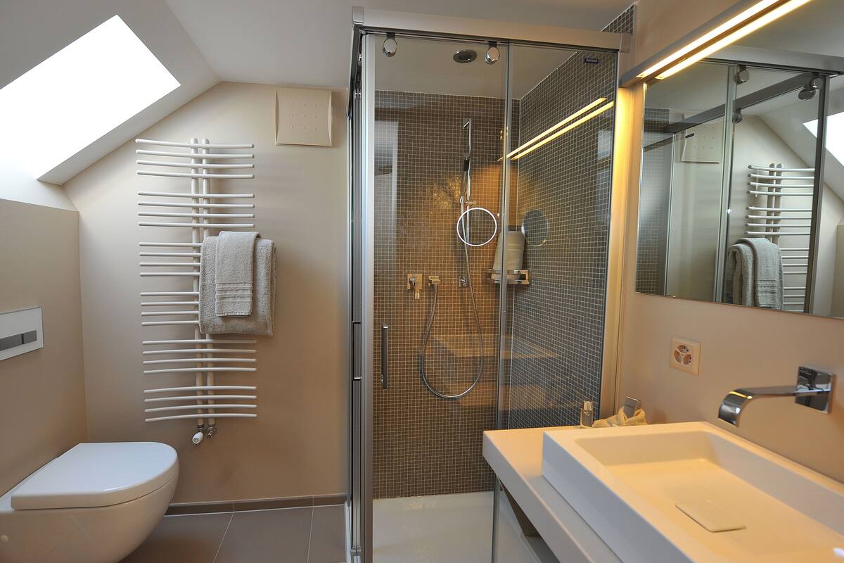 A modern bathroom with a glass-enclosed shower, a white sink, and a towel rack.
