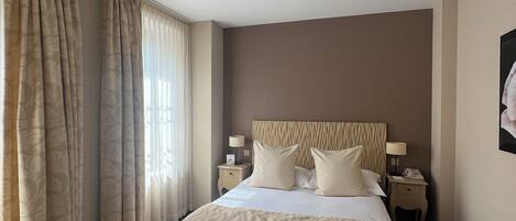 Une chambre d’hôtel avec un grand lit, deux tables de chevet avec des lampes, une chaise et un bureau avec un ordinateur portable.