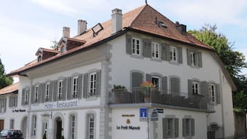 Ein zweistöckiges Gebäude mit einem Schild, auf dem „Hôtel – Restaurant Le Petit Manoir“ steht.