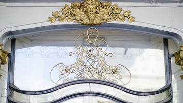 Een sierlijk architectonisch detail met een goudkleurig decoratief element boven een raam.