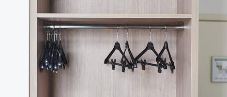 Une armoire en bois avec une tringle en métal et des cintres noirs.