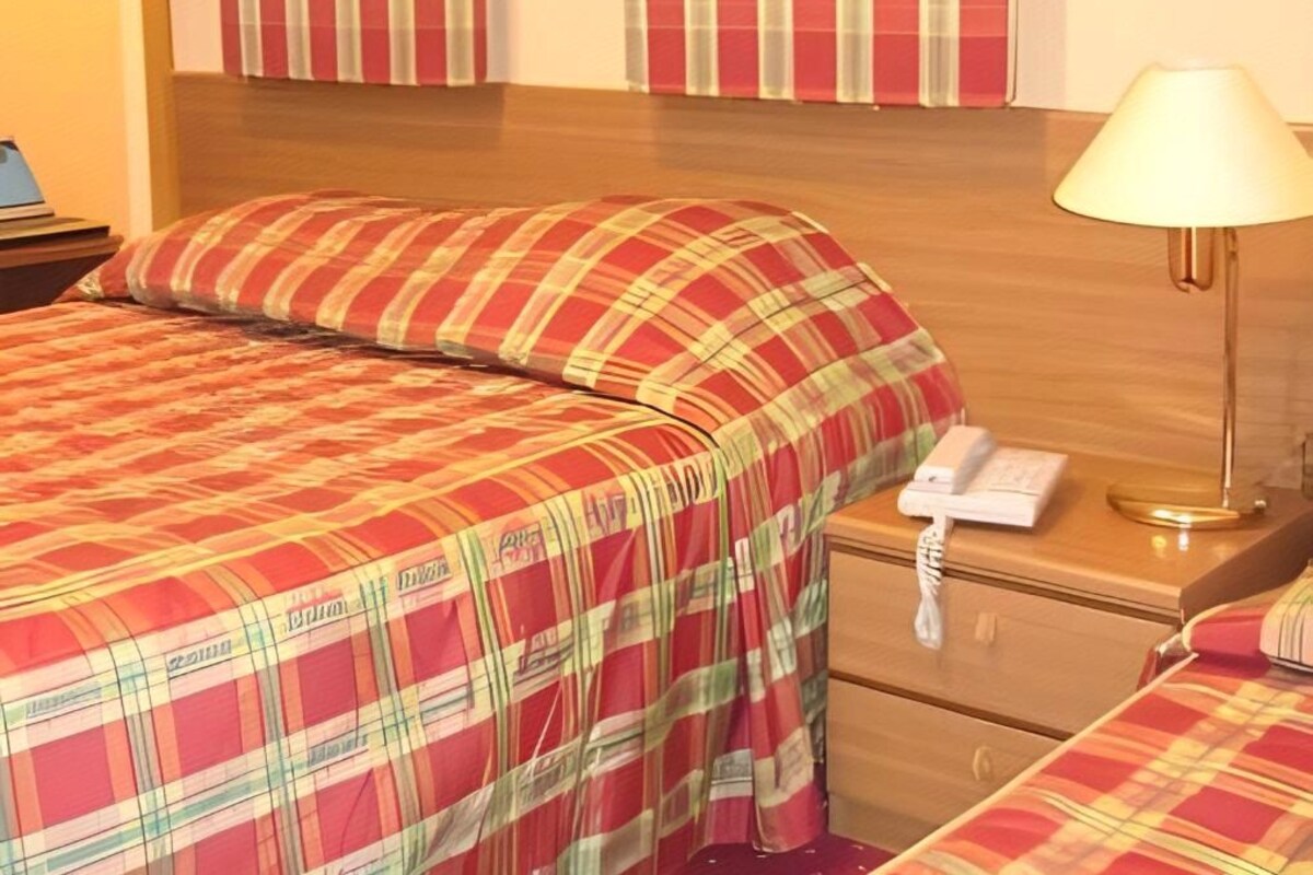 Une chambre d’hôtel avec un lit, une lampe de chevet, un téléphone et une table de chevet.