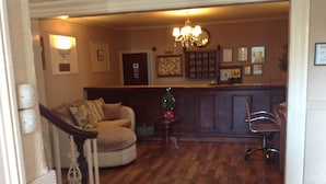 Un salon avec un canapé rond, un plancher en bois, un lustre et une petite table sur laquelle est posé un sapin de Noël.