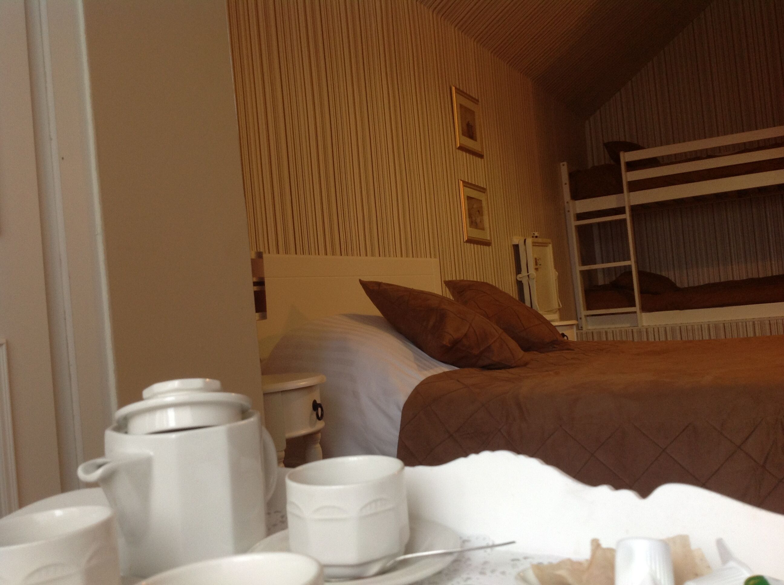 Ein Hotelzimmer mit einem Etagenbett, einem Nachttisch mit Lampe und einer Wand mit vertikalen Linien.