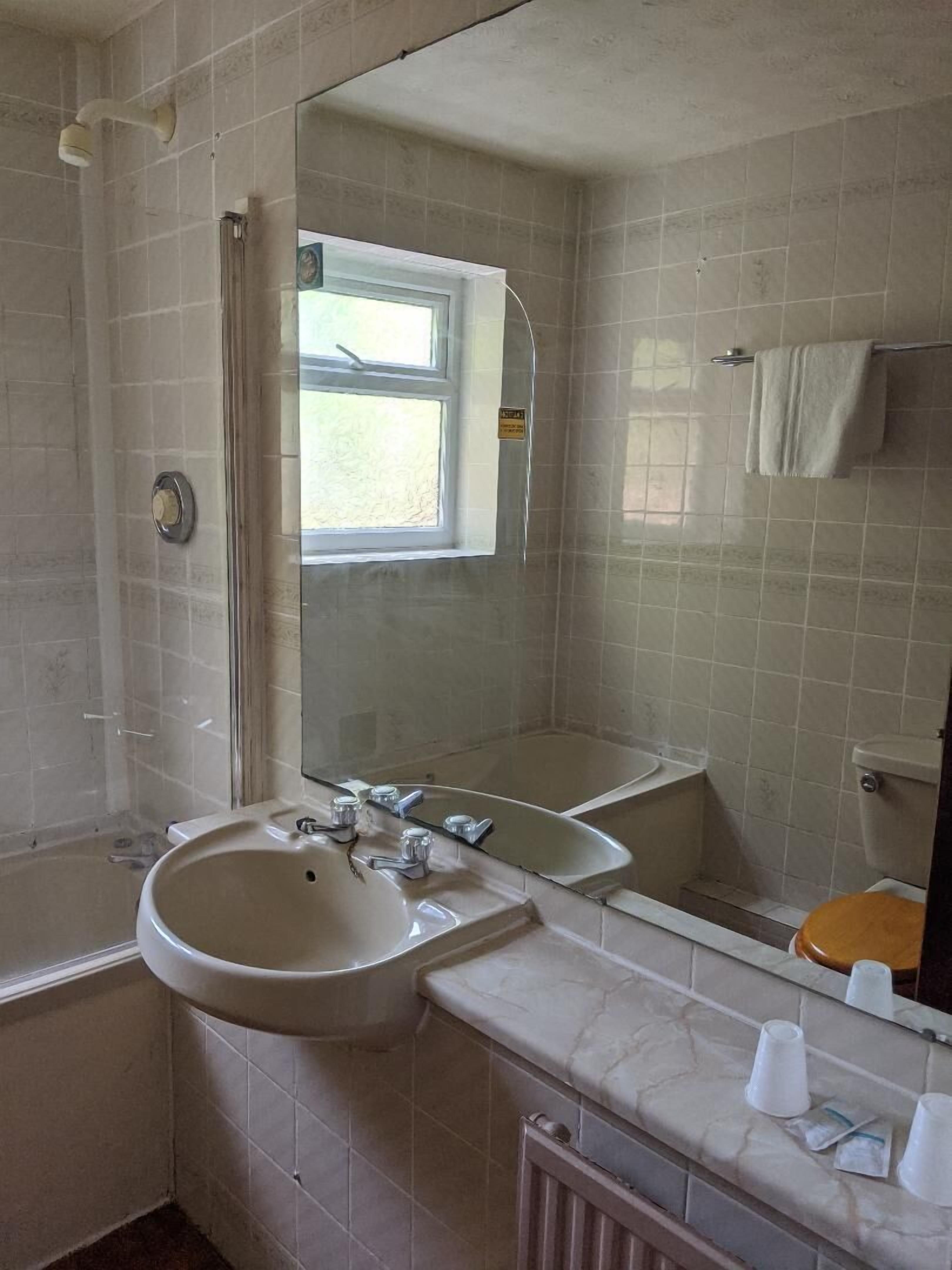 A bathroom with a sink, mirror, and window.