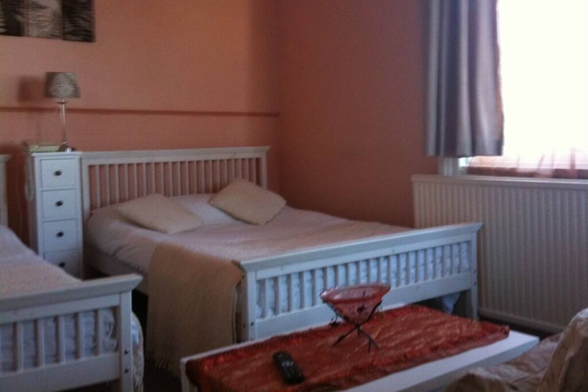 A bedroom with a bed, a nightstand, a lamp, and a window with curtains.