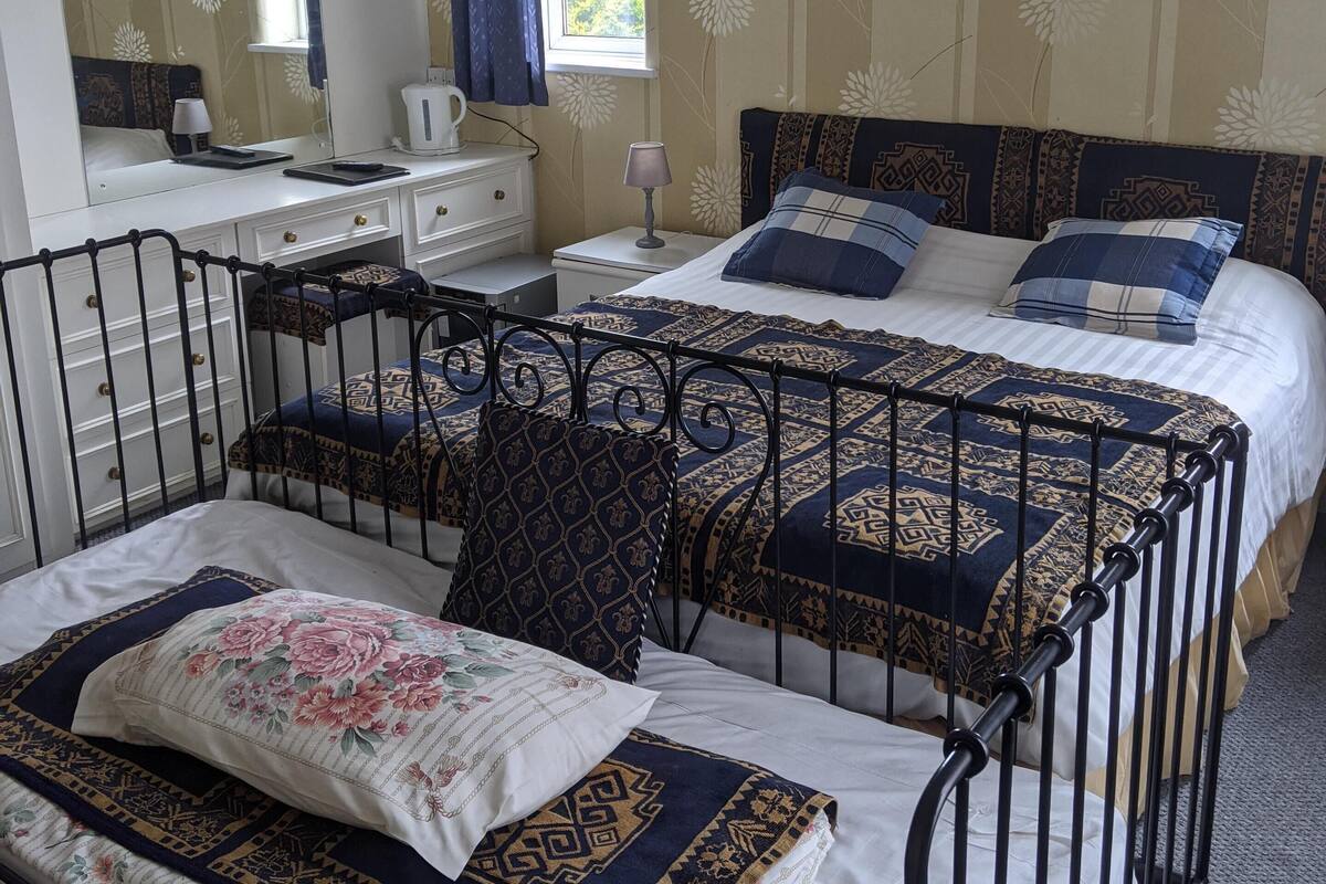 A bedroom with a bed, a dresser, a mirror, and a window with curtains.