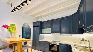 Una cocina moderna con armarios azul oscuro, una mesa de madera con dos sillas, un horno empotrado y un microondas.