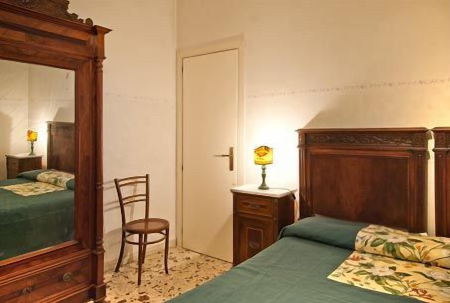 Un dormitorio con una cama de madera, una silla, una mesita de noche y un espejo.