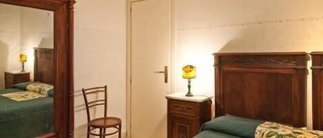 Un dormitorio con una cama de madera, una silla, una mesita de noche y un espejo.