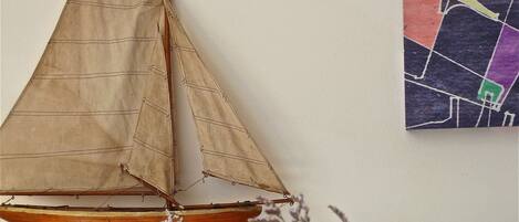 A model sailboat on a stand with a wall map in the background.