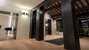 Un interior moderno con piso de madera, pilares negros y pared de piedra.