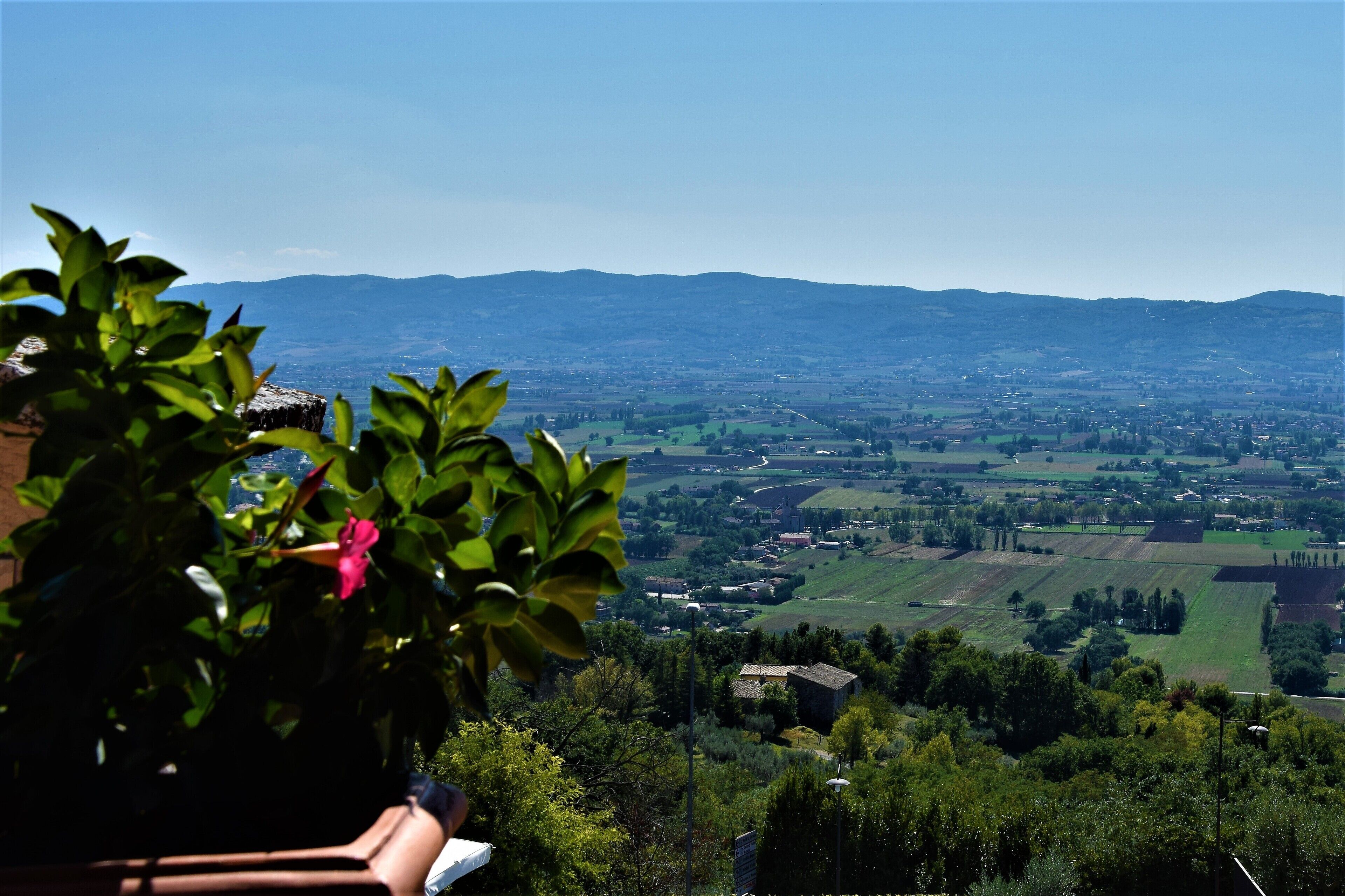 Vista panorámica de un valle con colinas onduladas y el perfil distante de una ciudad.