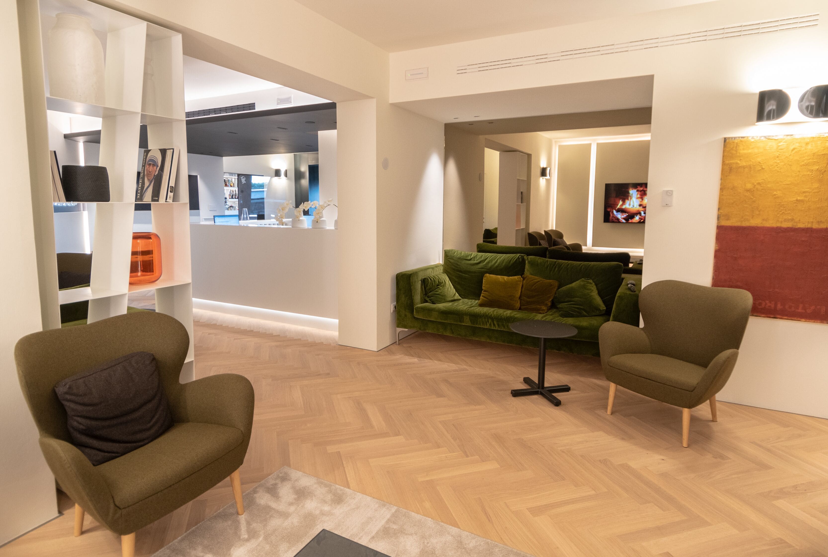 A modern living room with a green sofa, two armchairs, and a small table.