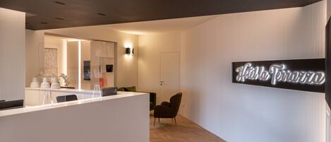 A modern reception area with a white reception desk, a green chair, and a wall-mounted sign that reads "Hotel Terra."