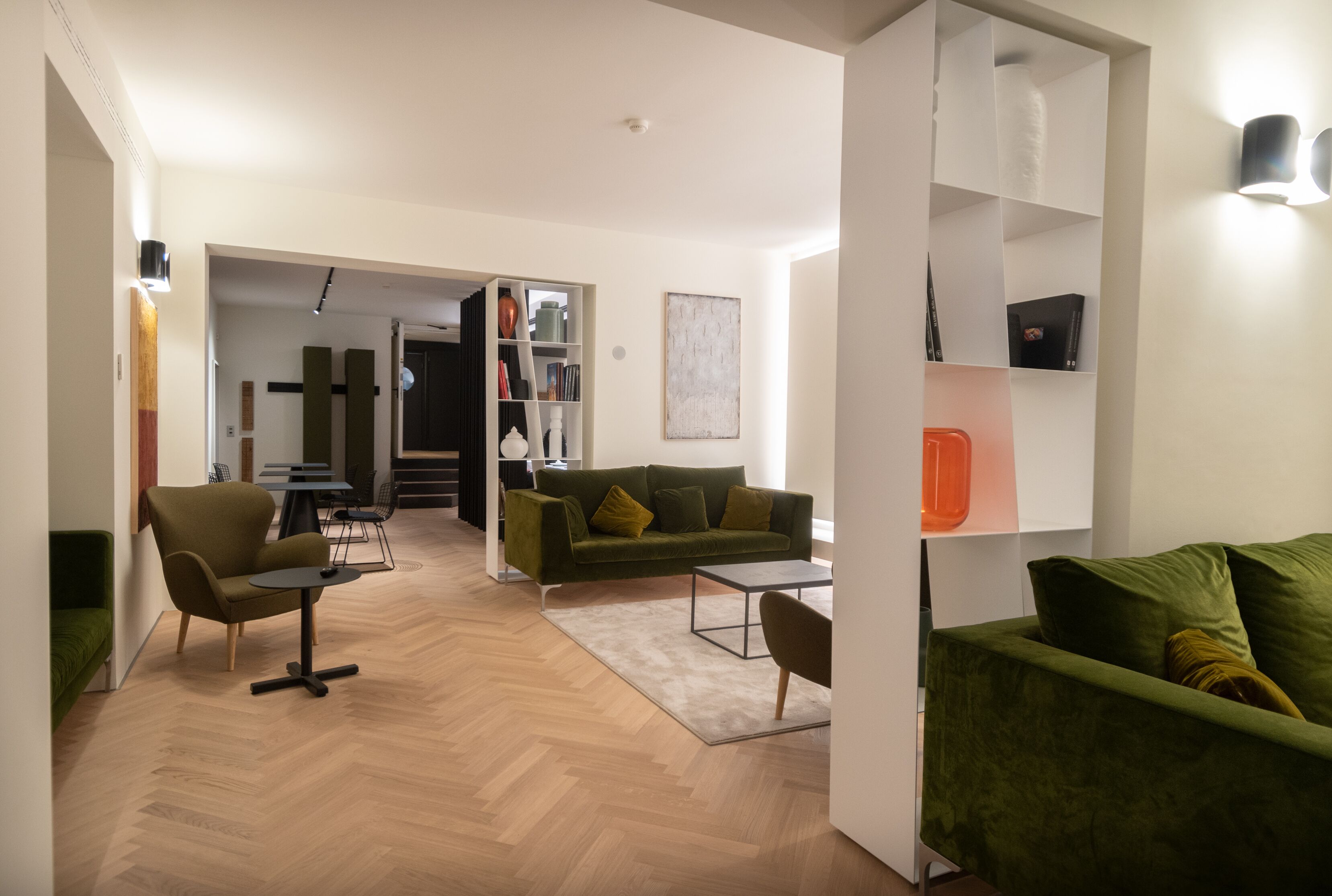 Una sala moderna con un sofá verde, una mesita redonda y una estantería.