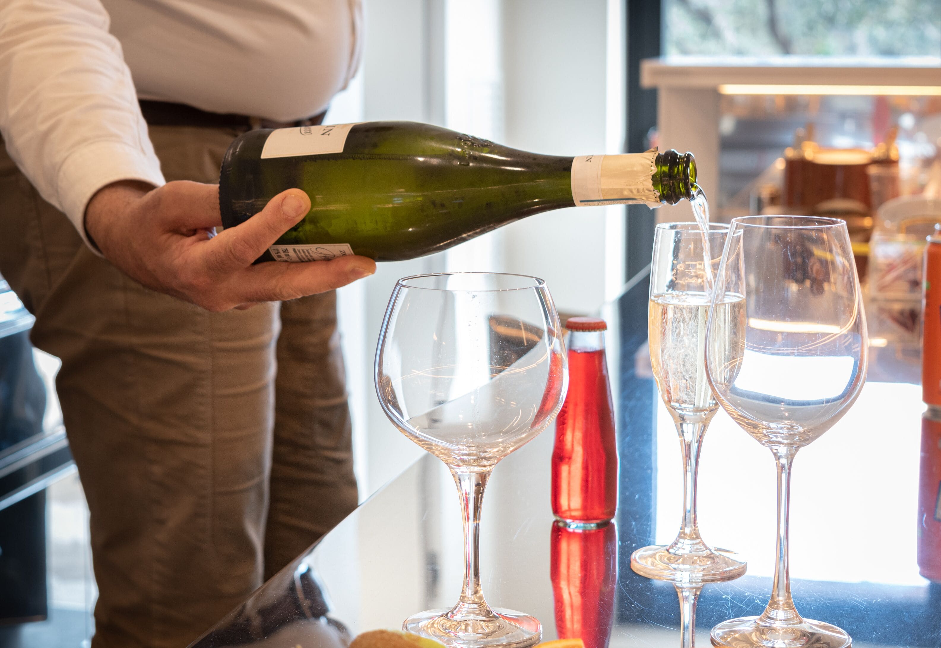 A person pouring wine into glasses.