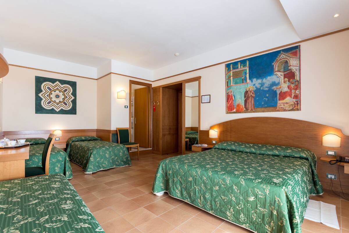 A hotel room with two beds, a desk, and a painting on the wall.