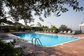 Una piscina al aire libre, sillones reclinables de piscina