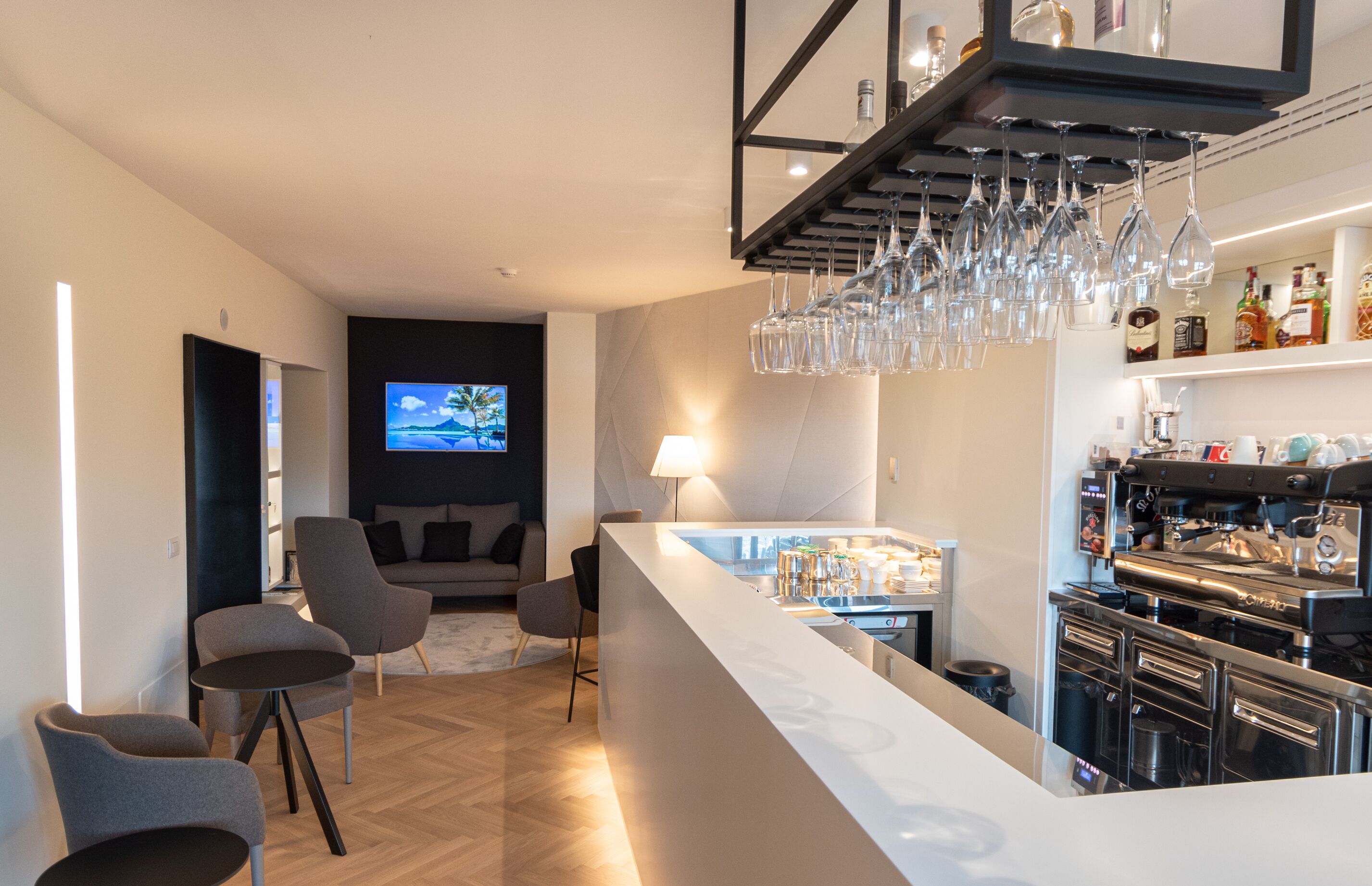 A modern living room with a bar area, a television, and a coffee machine.