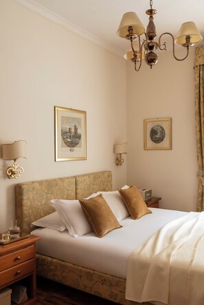Une chambre d’hôtel comprenant un lit, une table de chevet, une lampe et deux cadres photos accrochés au mur.